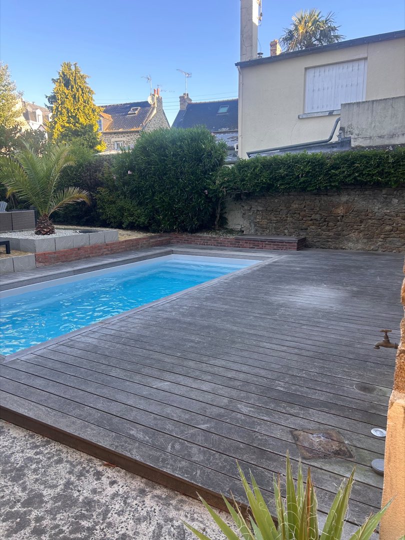 Avant nettoyage – Terrasse en bois exotique autour d’une piscine à Rennes : le bois grisé par les UV retrouve sa teinte chaude et profonde.